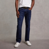 Person wearing blue jeans and a white shirt against a grey background